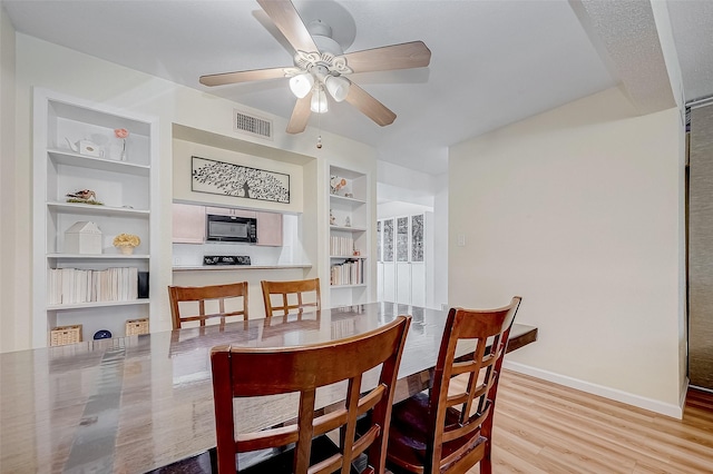 dining area featuring ceiling fan, light wood-type flooring, and built in shelves