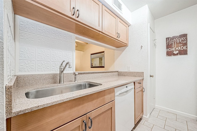 kitchen with white dishwasher, light stone countertops, sink, and light tile patterned floors