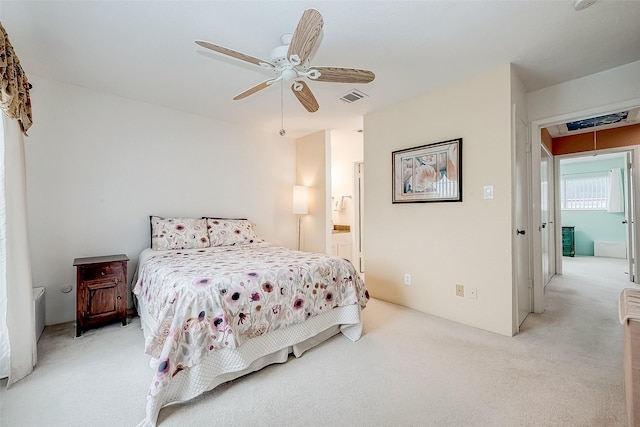 carpeted bedroom with ensuite bath and ceiling fan