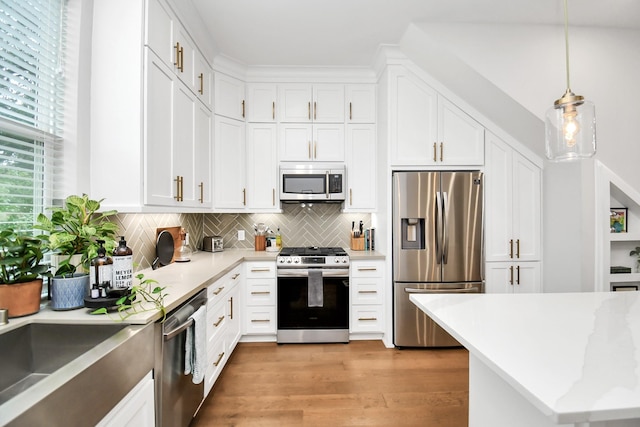 kitchen with stainless steel appliances, white cabinets, light wood-type flooring, tasteful backsplash, and pendant lighting