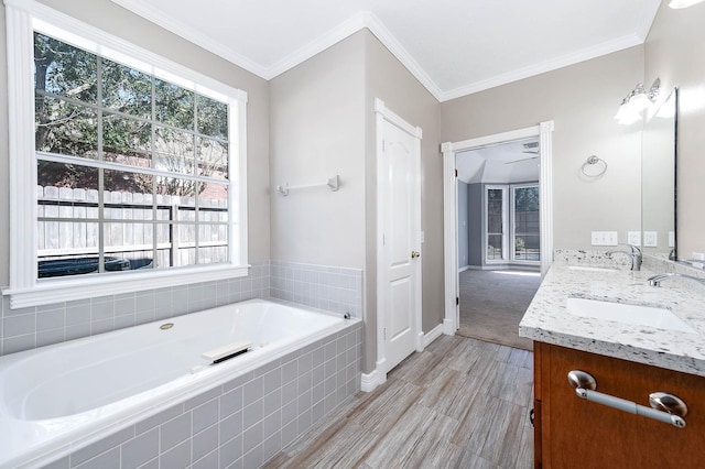 bathroom with vanity, ornamental molding, and tiled bath