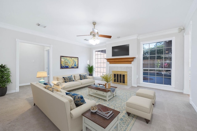 living room featuring a fireplace, light carpet, ceiling fan, and crown molding