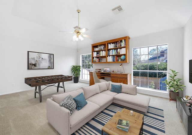 living room featuring light colored carpet, ceiling fan, and a healthy amount of sunlight