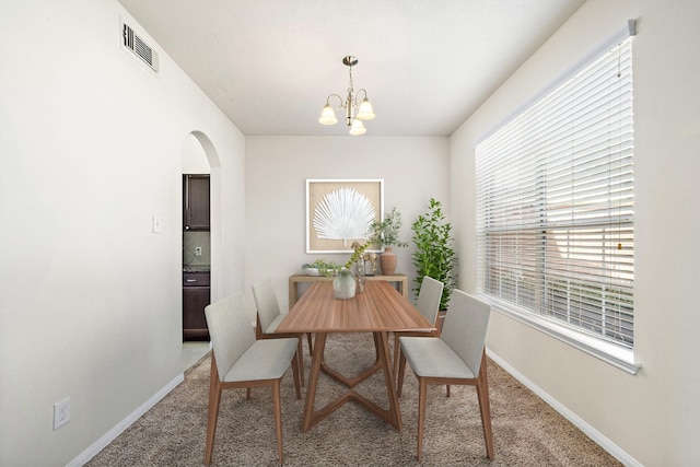 carpeted dining space with a notable chandelier