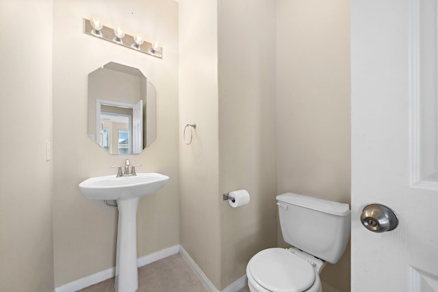 bathroom with toilet, tile patterned flooring, and sink