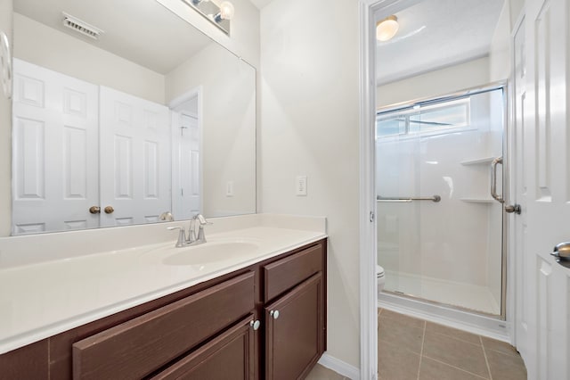 bathroom featuring vanity, tile patterned flooring, a shower with shower door, and toilet