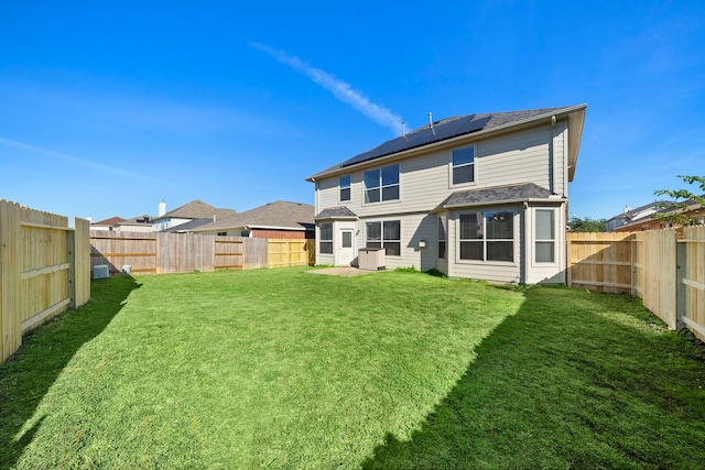 back of house featuring a lawn and solar panels