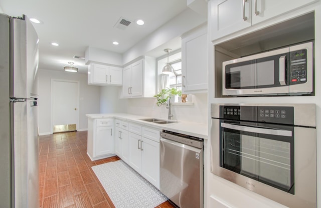 kitchen featuring hanging light fixtures, white cabinetry, appliances with stainless steel finishes, and sink