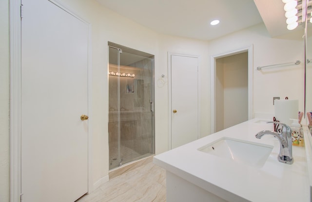 bathroom featuring a shower with door and vanity