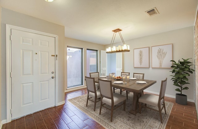 dining space featuring visible vents, baseboards, dark wood-style flooring, and an inviting chandelier