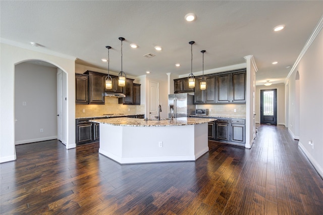 kitchen featuring stainless steel refrigerator with ice dispenser, decorative light fixtures, a kitchen island with sink, and decorative backsplash