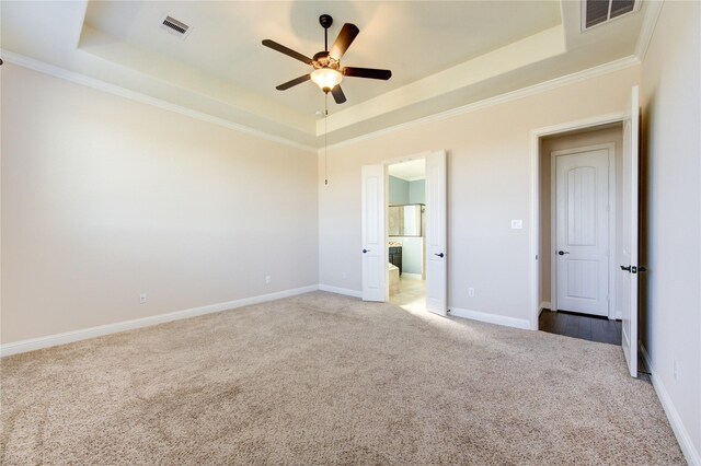 unfurnished bedroom featuring a tray ceiling, carpet, ceiling fan, and ensuite bathroom