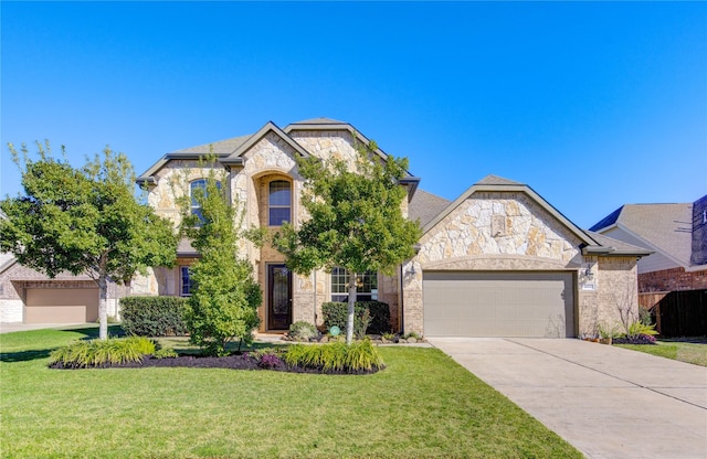 french provincial home with an attached garage, a front yard, driveway, and stone siding