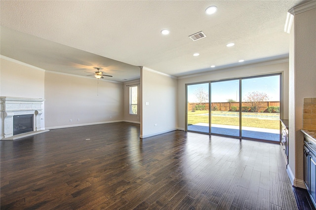unfurnished living room featuring crown molding, a fireplace with raised hearth, a ceiling fan, and visible vents