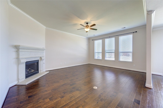 unfurnished living room with dark wood-style flooring, ceiling fan, a fireplace with raised hearth, baseboards, and ornamental molding