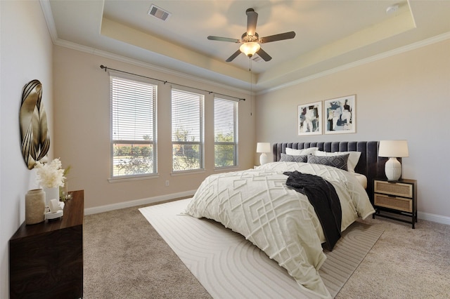 bedroom with ornamental molding, a tray ceiling, light colored carpet, and visible vents