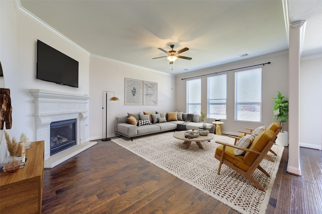 living room with crown molding, a glass covered fireplace, wood finished floors, baseboards, and ceiling fan