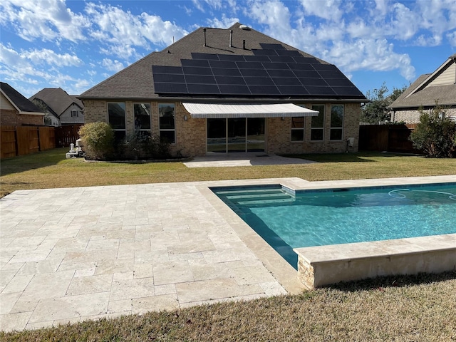 back of property featuring brick siding, a fenced in pool, solar panels, a lawn, and a patio