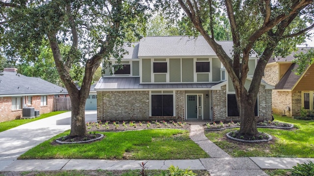 tudor-style house featuring central air condition unit and a front yard