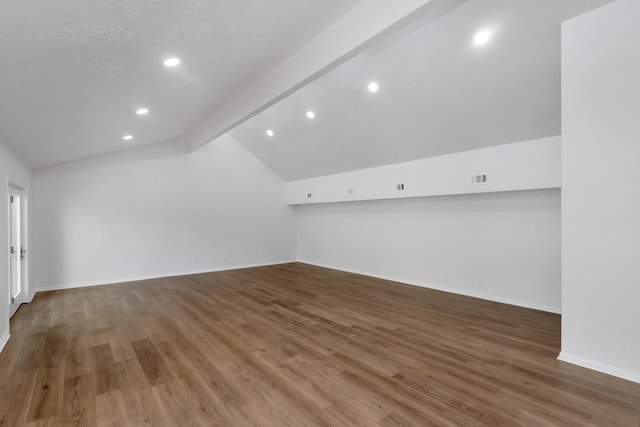 additional living space featuring dark wood-type flooring and lofted ceiling with beams