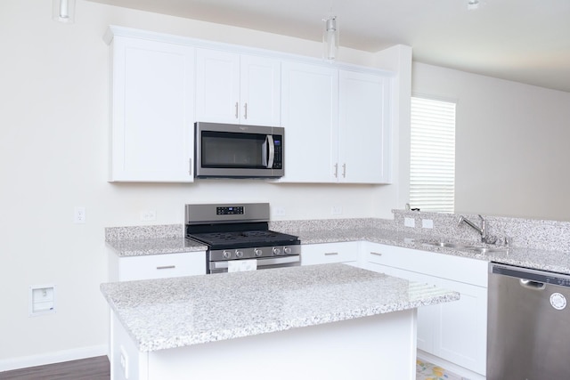 kitchen featuring appliances with stainless steel finishes, white cabinets, a kitchen island, and sink