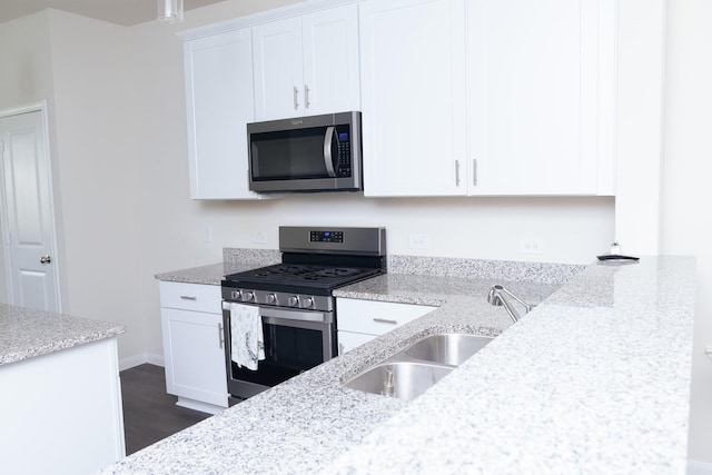 kitchen featuring sink, white cabinets, light stone counters, and appliances with stainless steel finishes