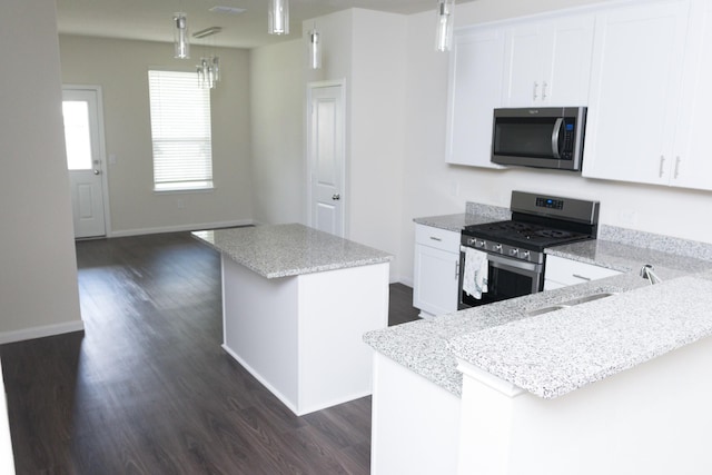 kitchen featuring stainless steel appliances, a center island, dark wood-type flooring, white cabinetry, and decorative light fixtures