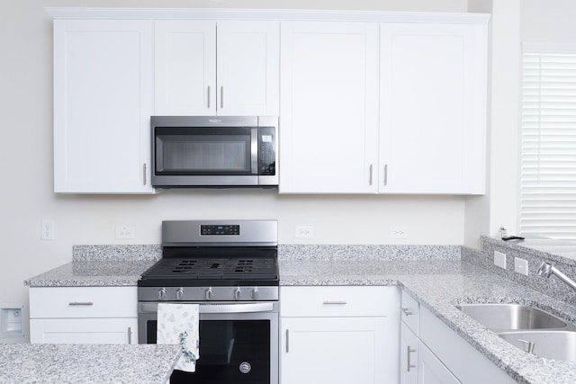 kitchen with stainless steel appliances, white cabinets, and sink