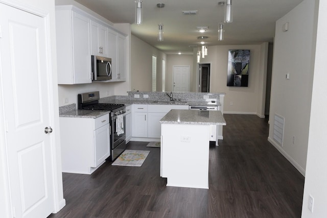 kitchen featuring light stone counters, kitchen peninsula, a center island, stainless steel appliances, and white cabinetry