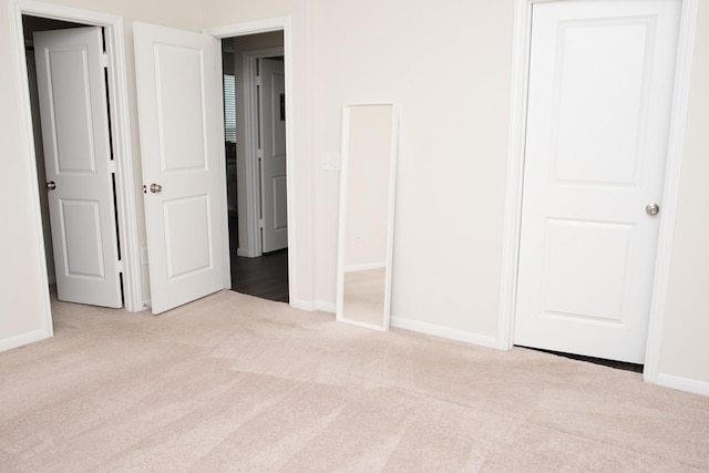 unfurnished bedroom with light colored carpet and a closet