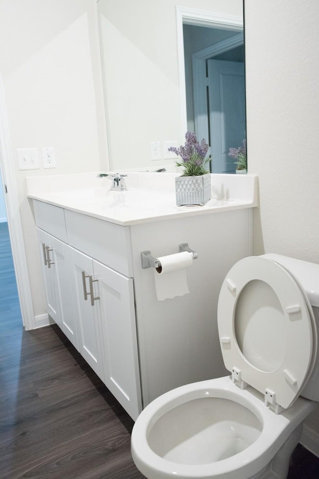 bathroom with wood-type flooring, vanity, and toilet