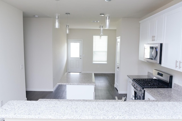 kitchen featuring stainless steel appliances, a kitchen island, white cabinetry, and hanging light fixtures