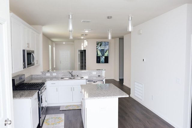 kitchen with appliances with stainless steel finishes, hanging light fixtures, a center island, sink, and white cabinetry