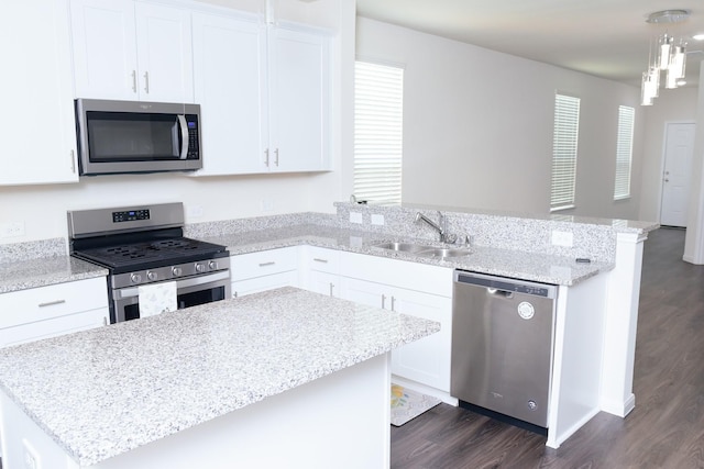 kitchen featuring white cabinets, appliances with stainless steel finishes, pendant lighting, and sink