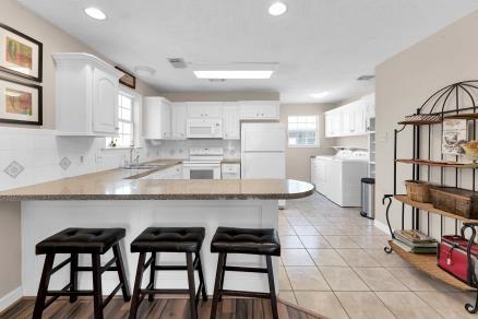 kitchen featuring white appliances, a kitchen breakfast bar, kitchen peninsula, white cabinets, and washing machine and clothes dryer