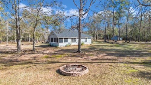 exterior space with an outdoor fire pit, a front yard, and a sunroom