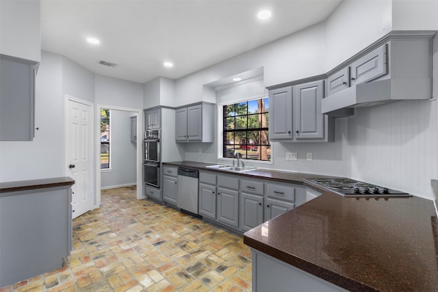 kitchen with sink, wall chimney range hood, black appliances, and gray cabinets