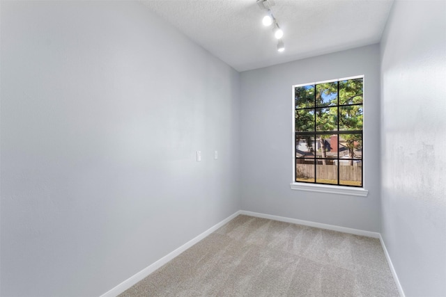 carpeted spare room featuring a textured ceiling and a wealth of natural light