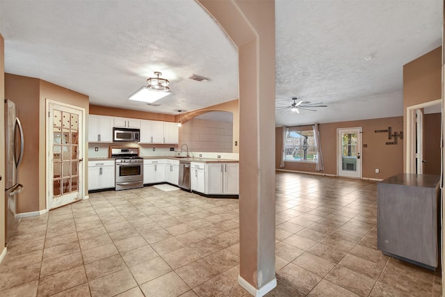 kitchen featuring white cabinets, appliances with stainless steel finishes, decorative backsplash, and sink