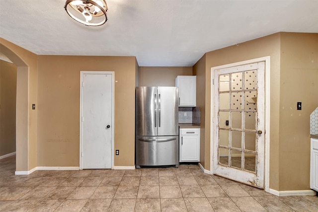 kitchen featuring white cabinets, tasteful backsplash, and stainless steel refrigerator