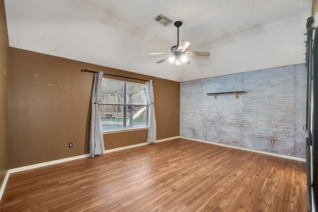 spare room featuring brick wall, ceiling fan, and wood-type flooring