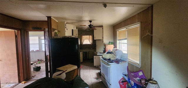 kitchen featuring ceiling fan, black fridge, white cabinetry, and wood walls