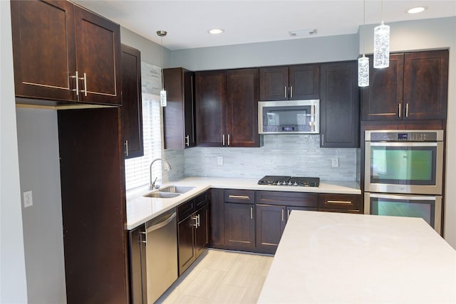 kitchen with stainless steel appliances, sink, decorative light fixtures, tasteful backsplash, and dark brown cabinetry