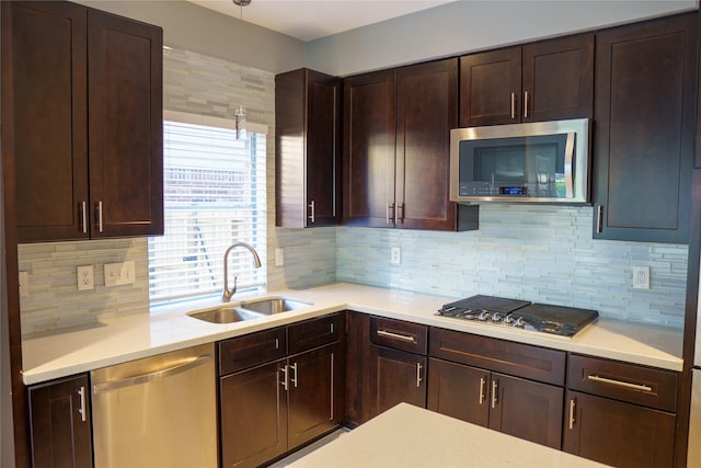 kitchen with sink, decorative light fixtures, tasteful backsplash, dark brown cabinets, and appliances with stainless steel finishes