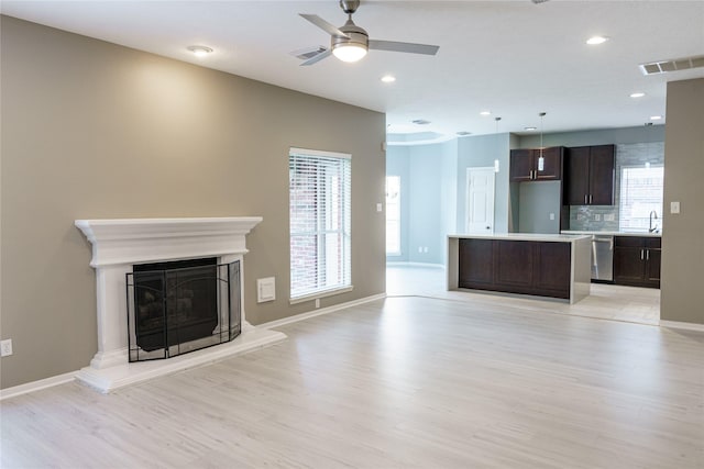 unfurnished living room featuring ceiling fan, light wood-type flooring, and plenty of natural light