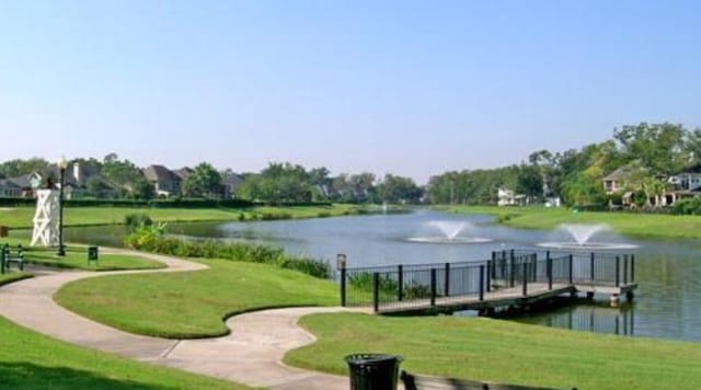 view of home's community with a water view and a yard