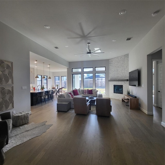 living room with ceiling fan, dark hardwood / wood-style flooring, and a fireplace