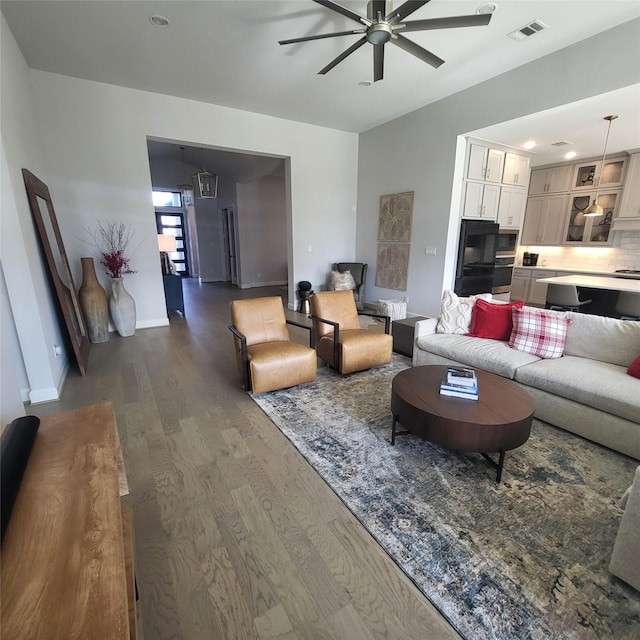 living room featuring ceiling fan and dark wood-type flooring