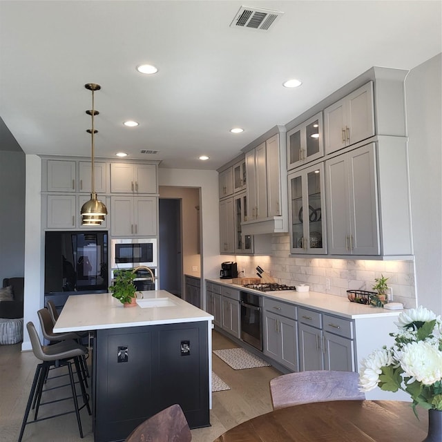 kitchen featuring sink, hanging light fixtures, gray cabinets, and stainless steel appliances