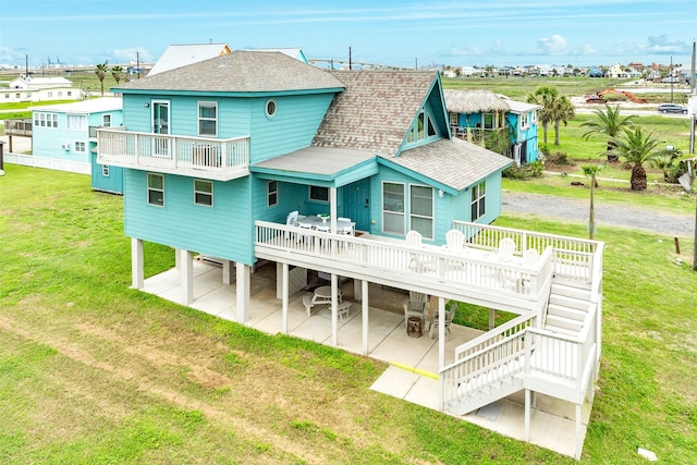 rear view of property with a lawn, a patio area, a balcony, and a wooden deck